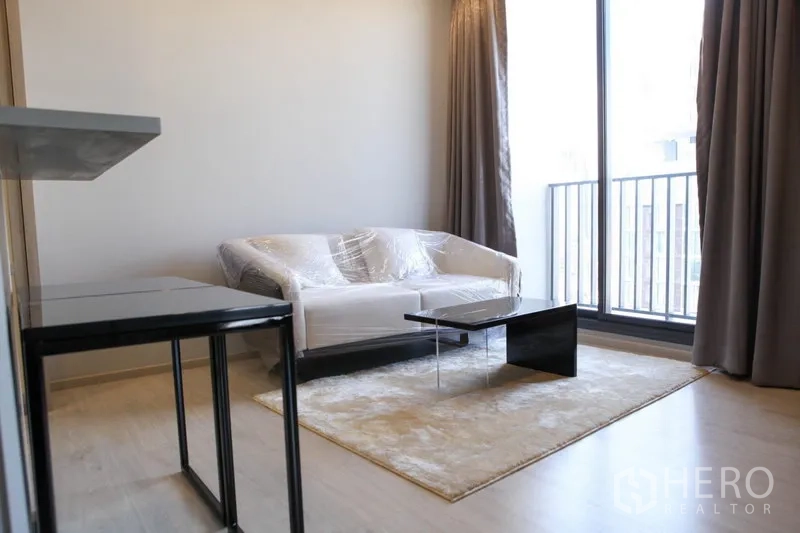 Condominium for rent in Watthana, Bangkok - Cozy living area with sofa, coffee table and floor-to-ceiling window to the balcony.