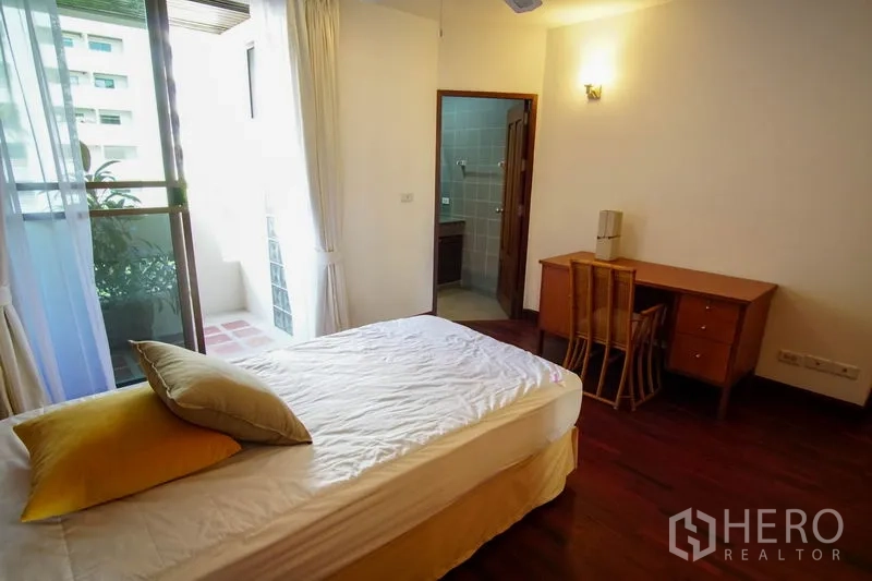 Apartment for rent in Watthana, Bangkok - Bedroom with sliding door to a small balcony and ensuite bathroom, plus a work desk.