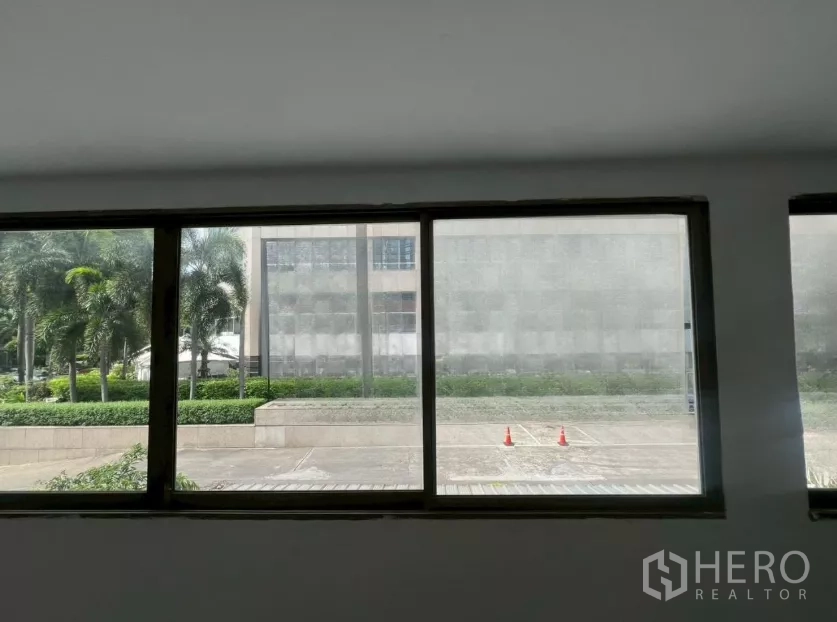 Retail Space for rent in Pathum Wan, Bangkok - View through wide windows toward a palm-lined plaza and office building.