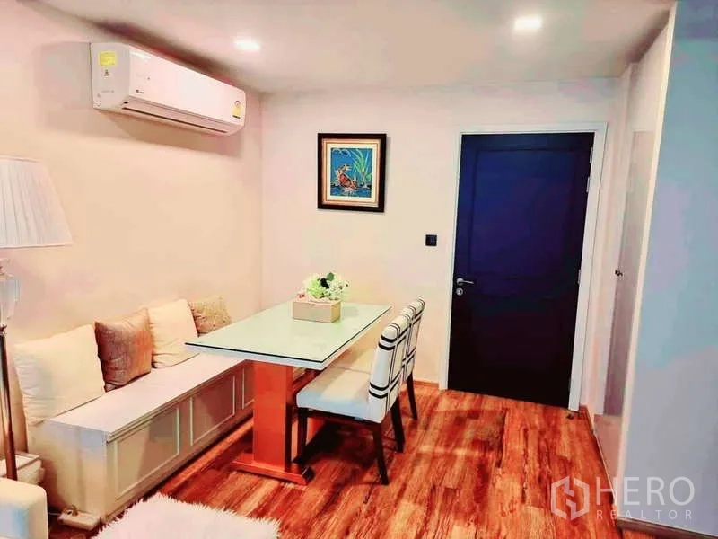 Condominium for sale in Bang Rak, Bangkok - Entrance dining corner with glass-top table, bench seat, two chairs and wood floors.