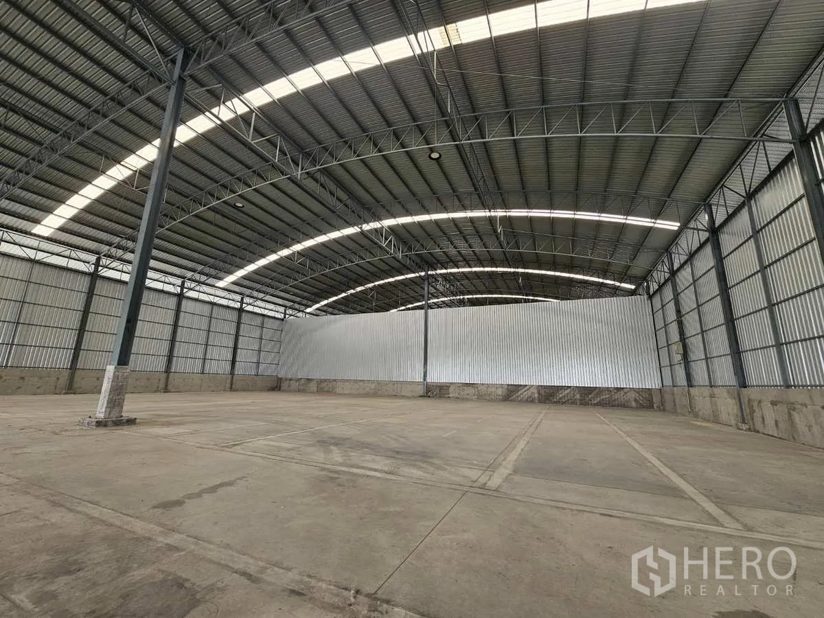 Warehouse for rent in Lam Luk Ka, Pathum Thani - Open storage space under an arched steel roof with a central column, ideal for racking.