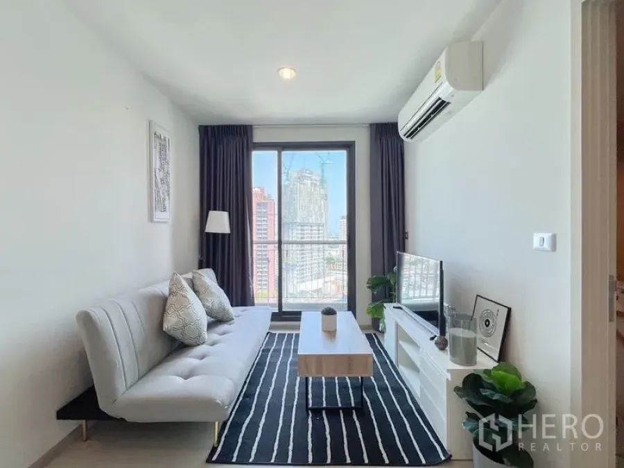 Condominium for rent or sale in Khlong Toei, Bangkok - Living area facing large window and skyline view from the sofa.