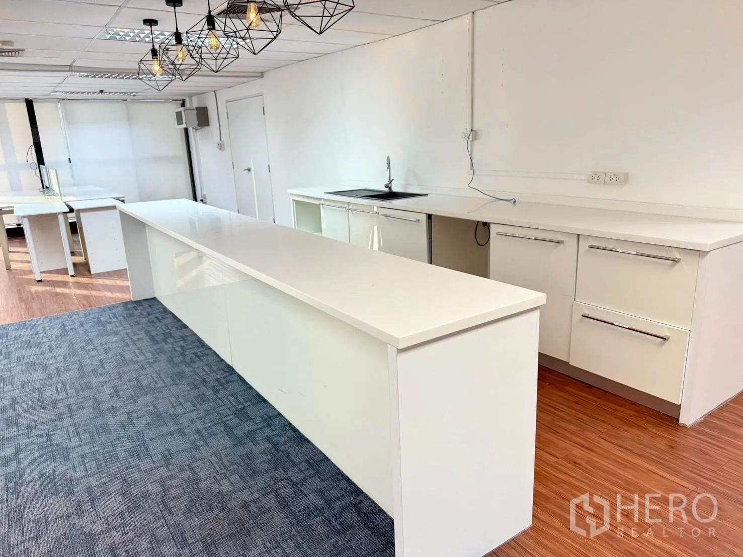 ออฟฟิศ for rent in Watthana, Bangkok - มุมแพนทรีเคาน์เตอร์สีขาวยาว พร้อมอ่างล้างจาน ตู้เก็บของ และโคมไฟแขวน.