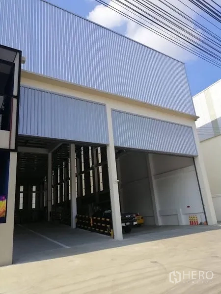 Warehouse for rent in Bang Phli, Samut Prakan - Front elevation with twin oversized roller doors and a covered parking/loading area.