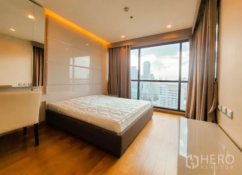 Condominium for rent in Bang Rak, Bangkok - Bedroom with large window, warm lighting and panoramic city view.