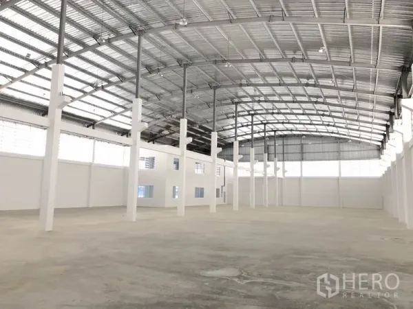 Warehouse for rent in Samut Prakan - Spacious warehouse interior with high arched steel roof, skylights, and open column layout.