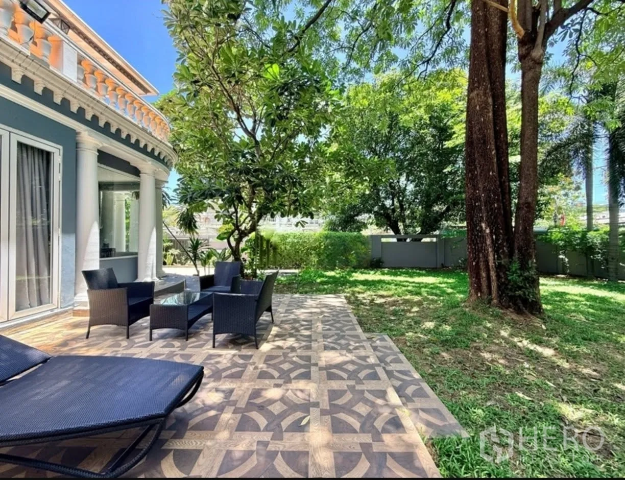 Detached House for rent in Phra Khanong, Bangkok - Outdoor patio with rattan seating and a sun lounger beside the lawn.