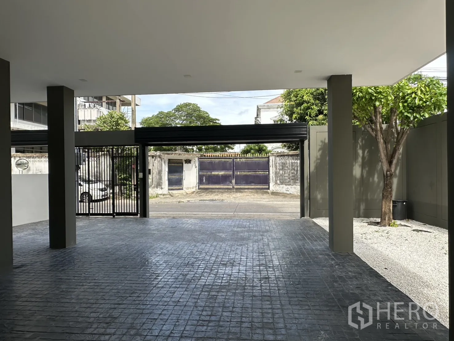 家庭办公室 for rent or sale in Suan Luang, Bangkok - 宽敞车棚朝向街道，金属滑动门与树荫相伴。