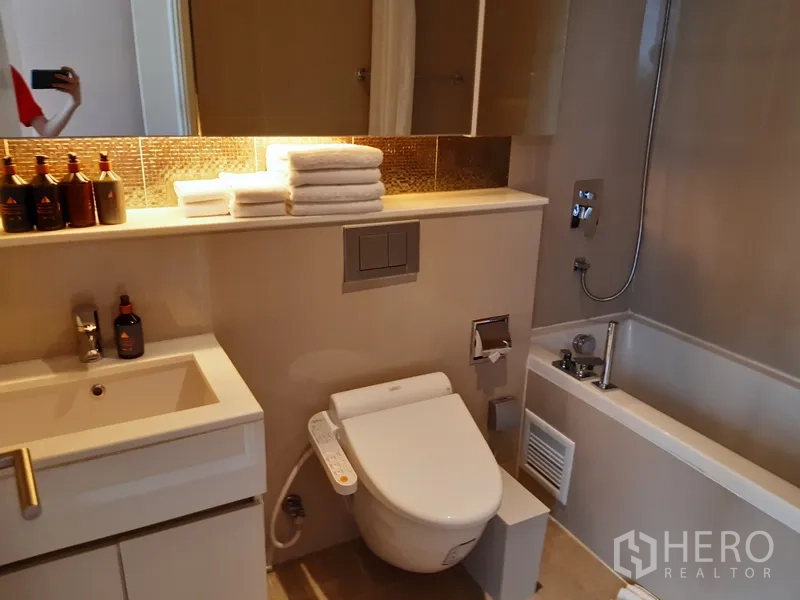 คอนโด ให้เช่าในWatthana, Bangkok - ห้องน้ำอีกห้องมีอ่างอาบน้ำ โถสุขภัณฑ์ระบบฉีดล้าง และชั้นวางพร้อมไฟ.
