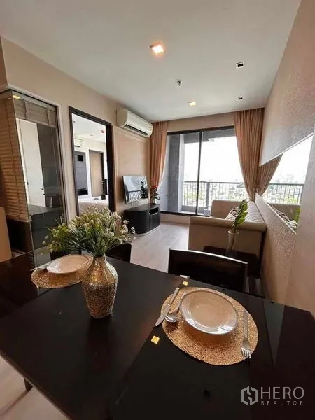 Condominium for rent or sale in Khlong Toei, Bangkok - Dining table for two overlooking a bright living room and balcony in a Phra Khanong condo.