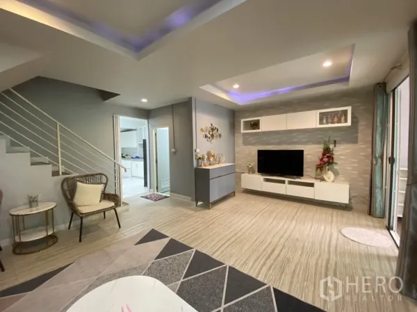 Townhouse for rent or sale - Modern living room with cove lighting, TV wall and staircase to the upper floor.