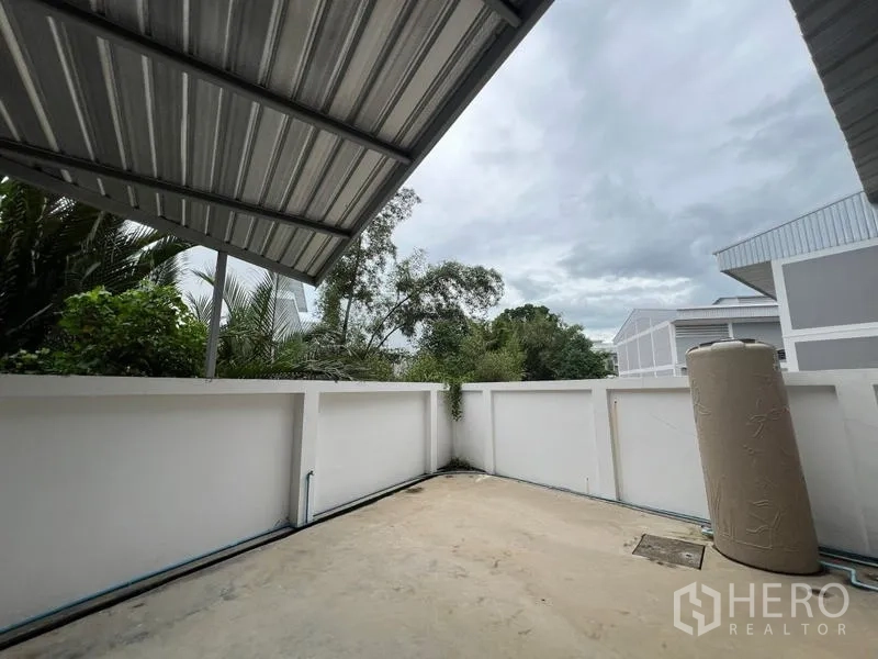 Factory for rent in Phra Samut Chedi, Samut Prakan - Small rear service patio under a metal roof with boundary walls and a standing water tank.