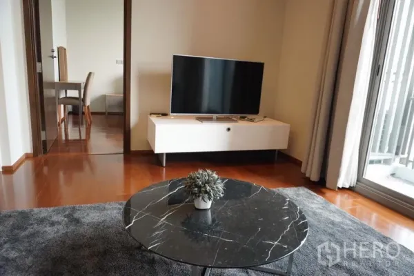 Condominium for rent in Watthana, Bangkok - Cozy lounge with TV console and marble coffee table opening to the bedroom.