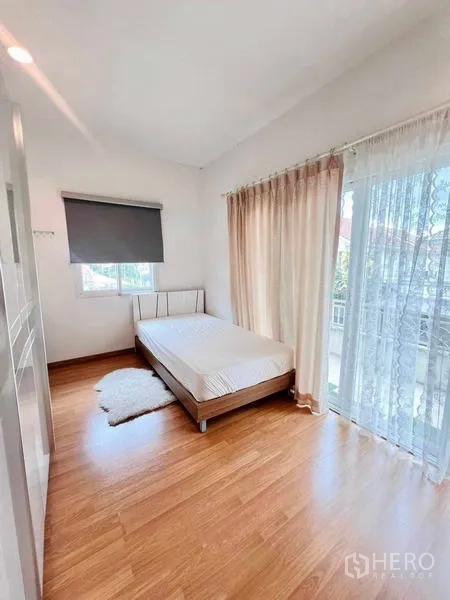 บ้าน ให้เช่าในLat Krabang, Bangkok - ห้องนอนสว่างพื้นไม้ มีประตูกระจกเปิดสู่ระเบียงและผ้าม่านโปร่ง