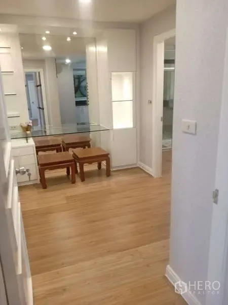 Condominium for rent in Khlong Toei, Bangkok - Hallway workspace with built‑in glass desk, stools, mirrors, and wood flooring.