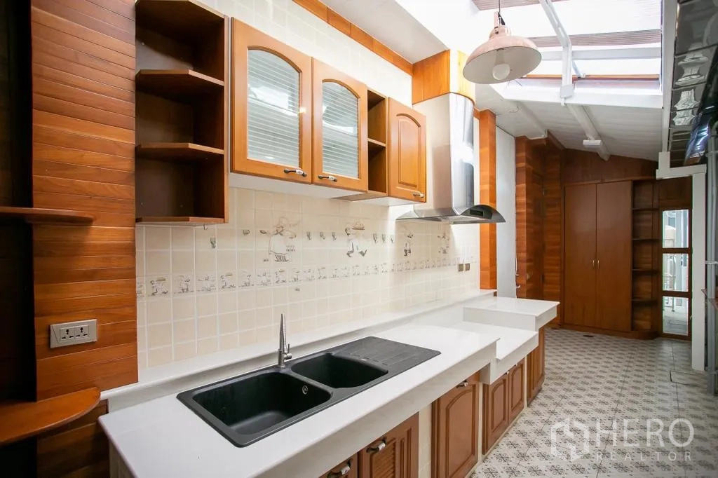 独栋房屋 for rent or sale in Huai Khwang, Bangkok - 带木柜、烟机与长操作台的厨房，位于天窗下。
