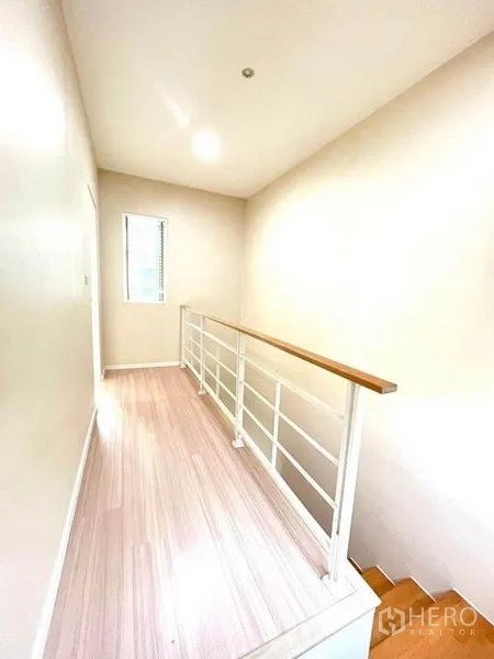 Townhouse for sale in Bang Kapi, Bangkok - Sunlit landing with white railing and a side window.