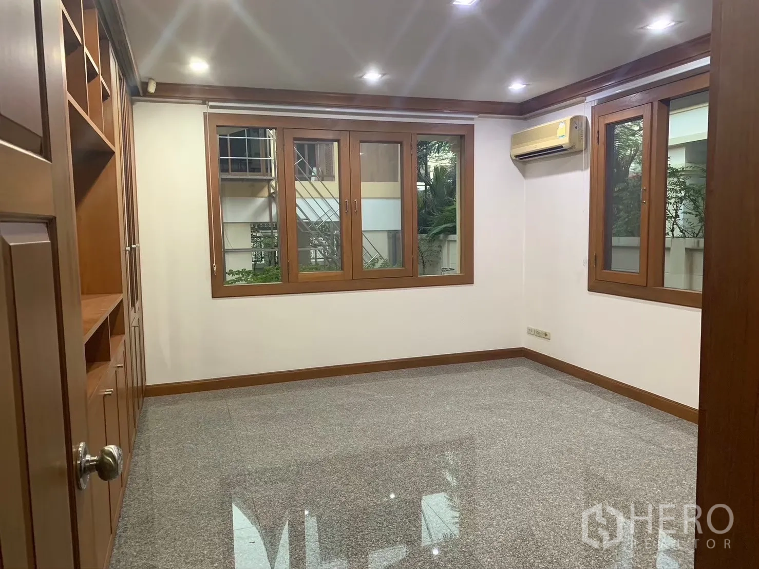 Detached House for rent in Watthana, Bangkok - Air-conditioned room with large windows, built-in storage and stone floor.