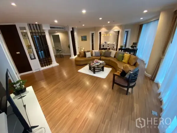 Apartment for rent in Watthana, Bangkok - Open-plan living area with wooden floors, recessed lighting and large wraparound windows.