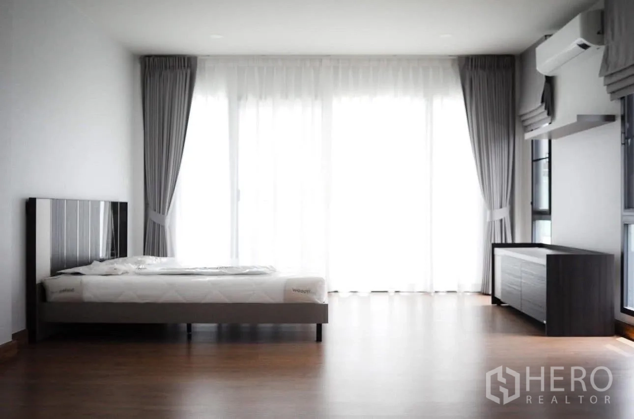 Detached House for rent in Bang Phli, Samut Prakan - Spacious bedroom with bed, dresser, air conditioner, and floor-to-ceiling windows.