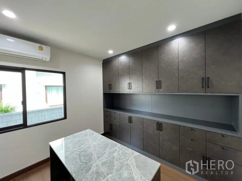 Detached House for sale in Saphan Sung, Bangkok - Home office or storage room with dark built-ins and marble island.