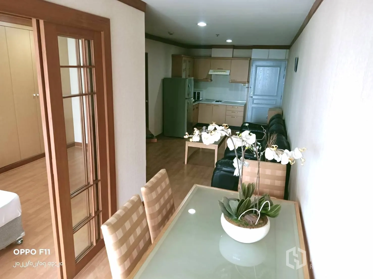 Condominium for rent in Khlong Toei, Bangkok - Dining nook with a glass-top table and orchid centerpiece beside the bedroom and kitchen.