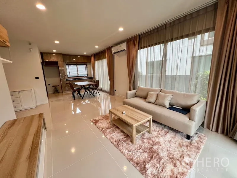 Detached House for rent in Bang Kapi, Bangkok - Open-plan living and dining area with sofa, rug and full-height curtains.