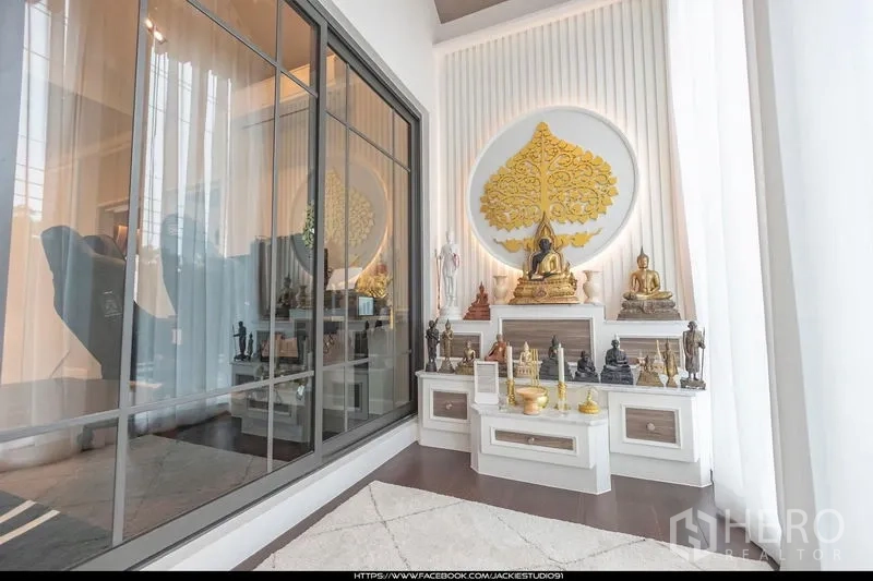 独立式住宅 出售在Pak Kret, Nonthaburi - 通透明亮的祈福/静心空间，内置神龛与金色菩提树墙饰，旁为大面积玻璃隔断。