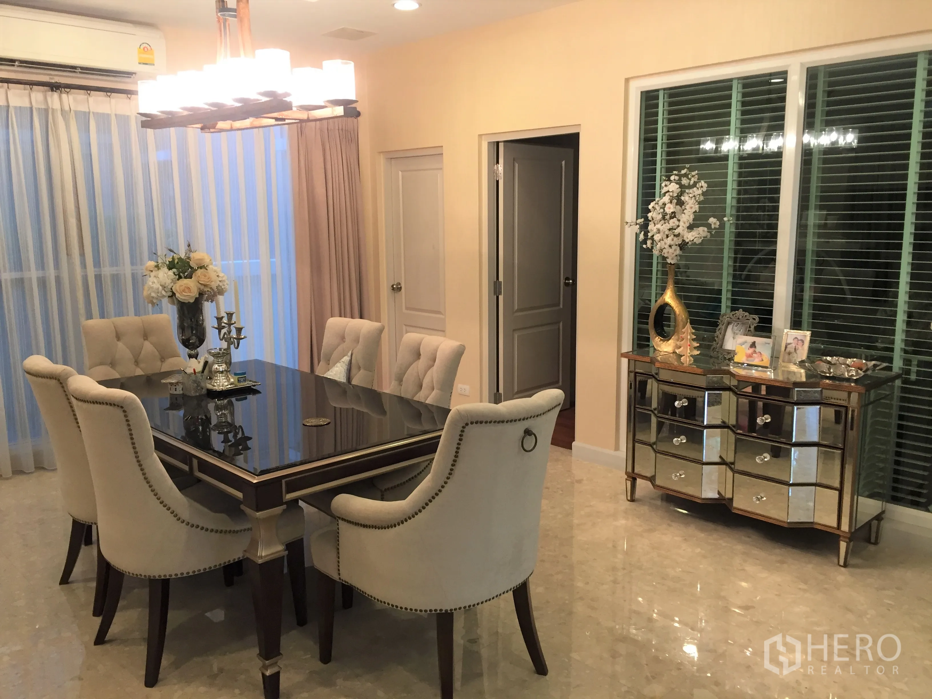 Detached House for sale in Saphan Sung, Bangkok - Dining room with six upholstered chairs, glossy table and mirrored sideboard under warm lighting.