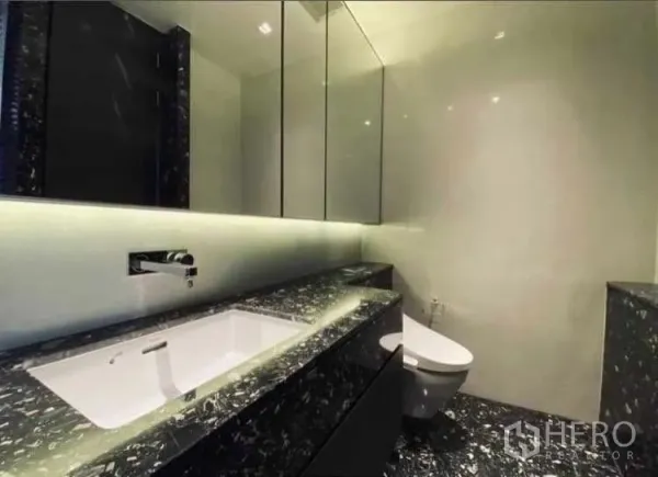 Condominium for rent or sale - Modern bathroom with marble vanity, backlit mirror and wall-hung toilet.