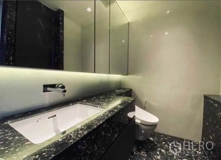 Condominium for rent or sale - Modern bathroom with marble vanity, backlit mirror and wall-hung toilet.