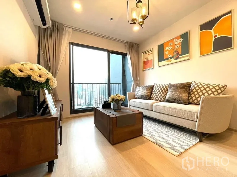 公寓 出租在Pathum Wan, Bangkok - 采光良好的客厅，米色沙发、木质茶几与推拉门通向阳台。