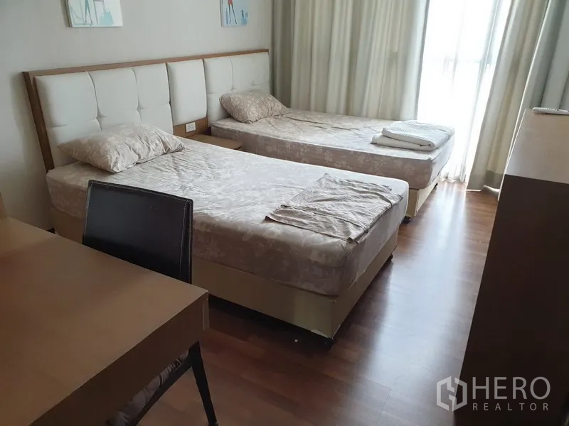 公寓 出租在Watthana, Bangkok - 次卧配两张单人床、书桌、木地板，推拉玻璃门通阳台。