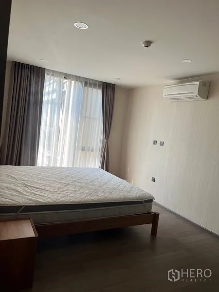 公寓 出租在Pathum Wan, Bangkok - 卧室设大窗、纱帘与遮光帘，壁挂空调与木地板。