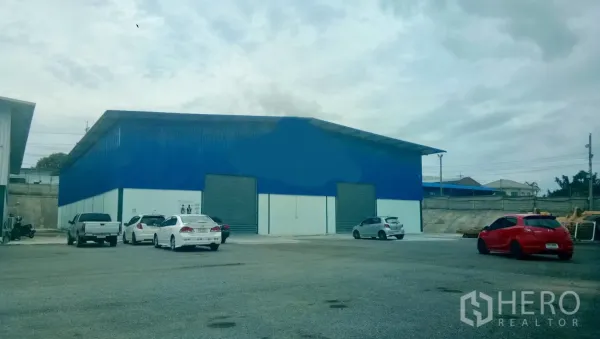 Warehouse for rent in Si Racha, Chon Buri - Blue warehouse exterior with twin roller shutter doors and wide parking and truck access.