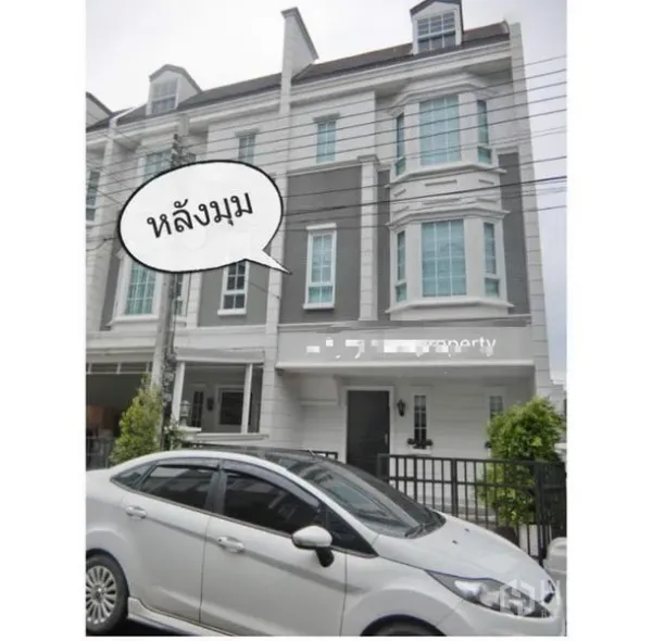 Townhouse for rent in Bang Kapi, Bangkok - Front facade of the townhouse row with tall windows and a driveway behind a black fence.