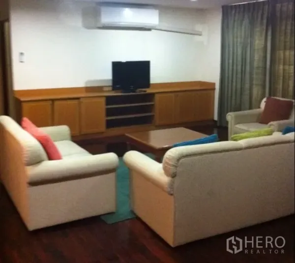 公寓 出租在Watthana, Bangkok - 客厅配奶油色沙发、木质电视柜与木地板。