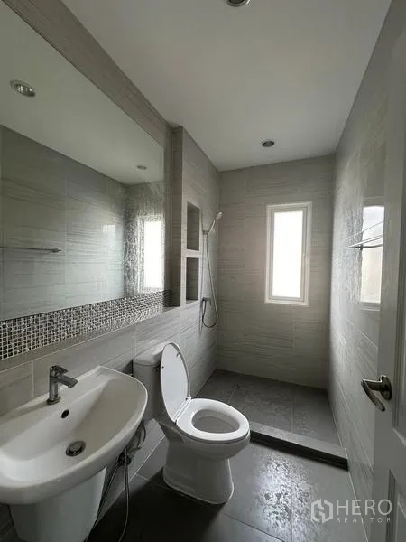 Detached House for sale in Bang Khen, Bangkok - Modern gray-tiled bathroom with shower niche, large mirror, and window.