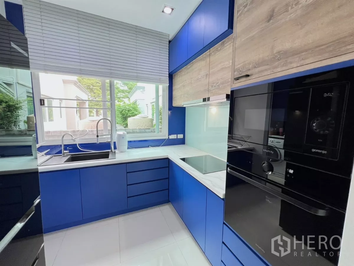 Detached House for rent or sale in Khlong Luang, Pathum Thani - Kitchen view with sink under window, built-in oven and ample storage.