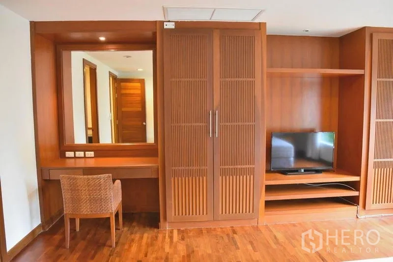 Apartment for rent in Sathon, Bangkok - Bedroom corner with vanity, TV shelf and wood cabinetry.
