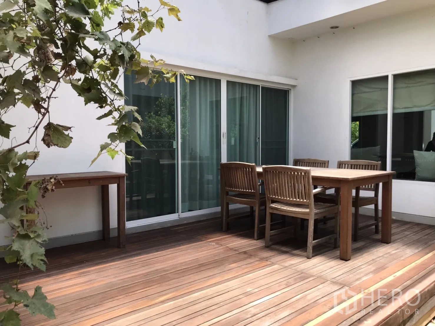 Detached House for rent or sale in Saphan Sung, Bangkok - Large wooden deck terrace with outdoor dining table and sliding glass doors.