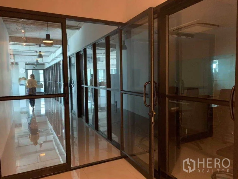 办公空间 出租在Phaya Thai, Bangkok - 走廊两侧为黑框玻璃隔间，通向独立办公室。
