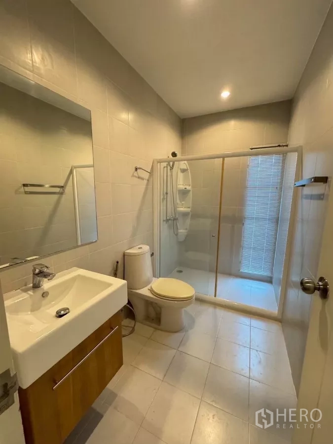 Townhouse for rent in Suan Luang, Bangkok - Bathroom with glass-enclosed shower, vanity and toilet.