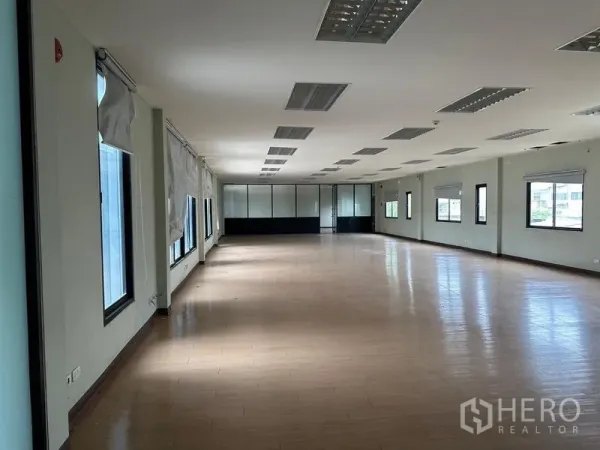Warehouse for rent in Prawet, Bangkok - Long office workspace with multiple windows and wood flooring.