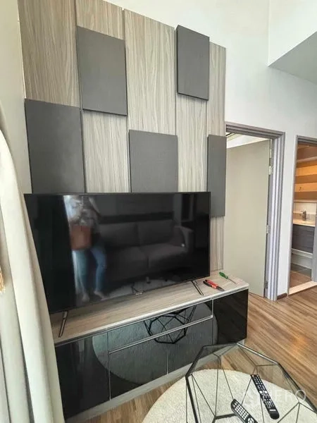 Condominium for rent or sale in Watthana, Bangkok - TV feature wall with decorative panels and media console in the living room.