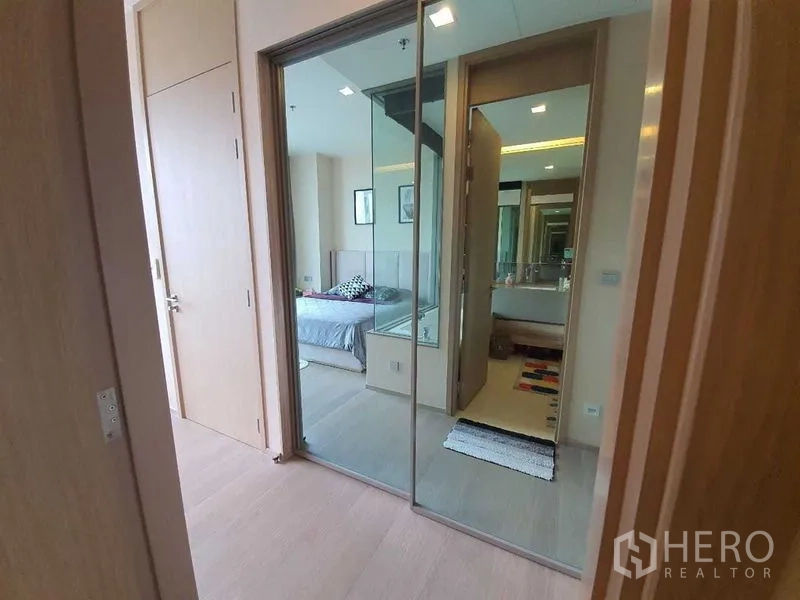公寓 出租或出售在Watthana, Bangkok - 入户走廊带镜面衣柜，通往卧室与玻璃隔断浴室。