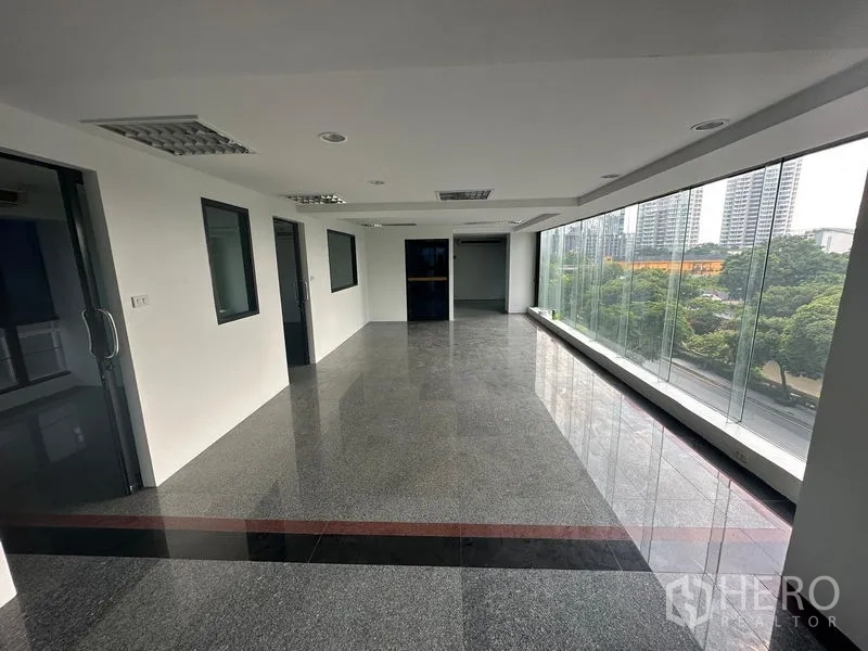 办公空间 出租在Sathon, Bangkok - 开放式办公区，整面落地玻璃，俯瞰树梢与城市高楼，位于沙吞区。