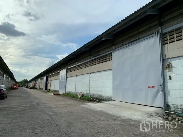 货栈 出租在Bang Phli, Samut Prakan - 成排仓库外观，金属推拉门与宽阔车道，适合卡车通行。