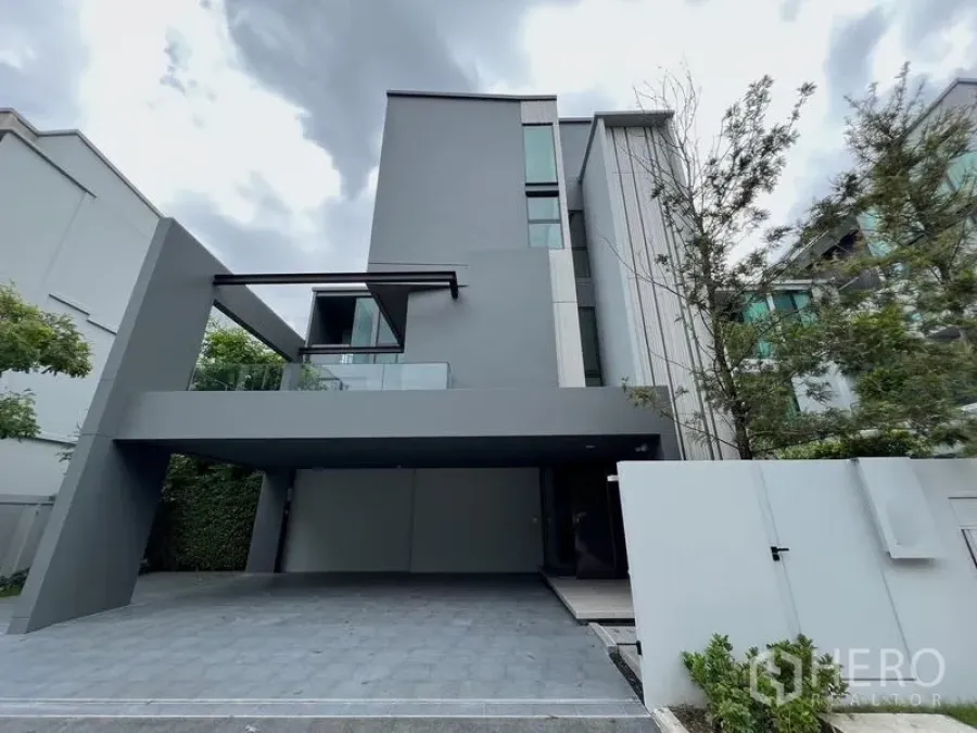 Detached House for rent or sale in Saphan Sung, Bangkok - Front elevation of a contemporary detached house with balcony and large carport.