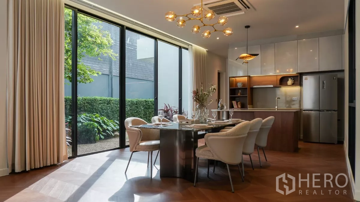 Detached House for rent or sale in Bang Kapi, Bangkok - Dining space with glass wall to patio, pendant lighting and table set for six.